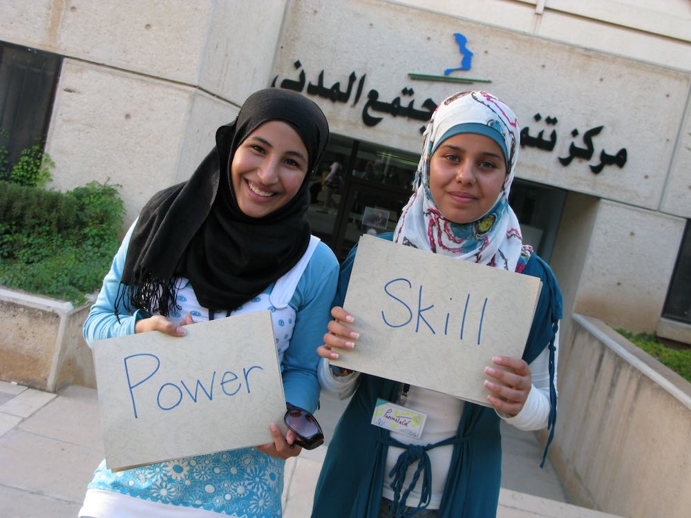 Two girls in Jordan holding signs that say power and skill
