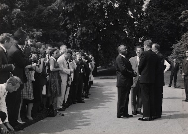 JFK and James Robinson talking in front of crowd on White House lawn in 1962 