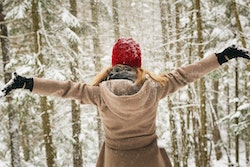 woman with red hat among snowy trees